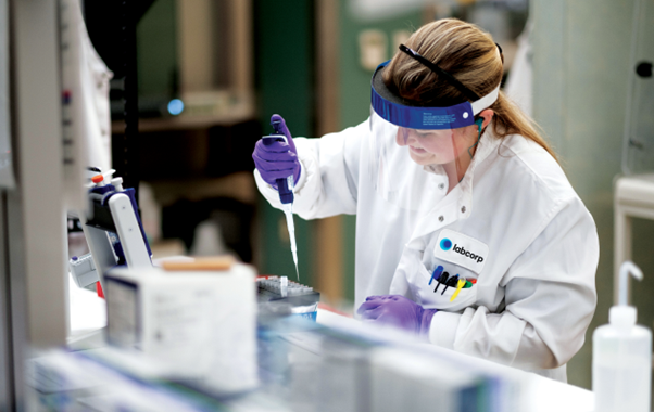 A woman wearing a lab coat engaged in scientific work, showcasing her dedication in a lab.
