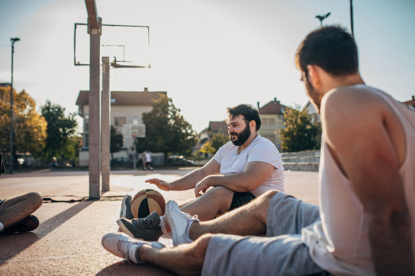 Men sit at basketball court.