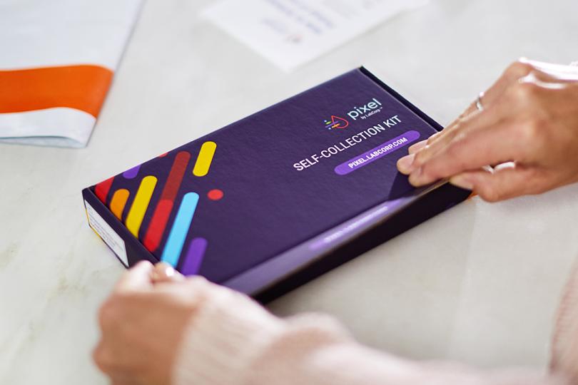 A person holding a Purple COVID-19 PCR self-collection test kit, showcasing a vibrant and cohesive color scheme.