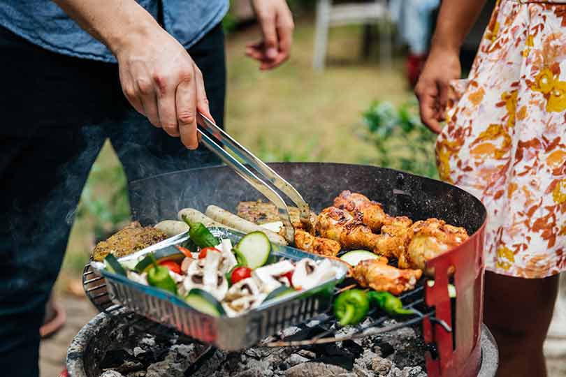 A close-up of people grilling food outside, mixing potential food allergens that could trigger people with food allergies.