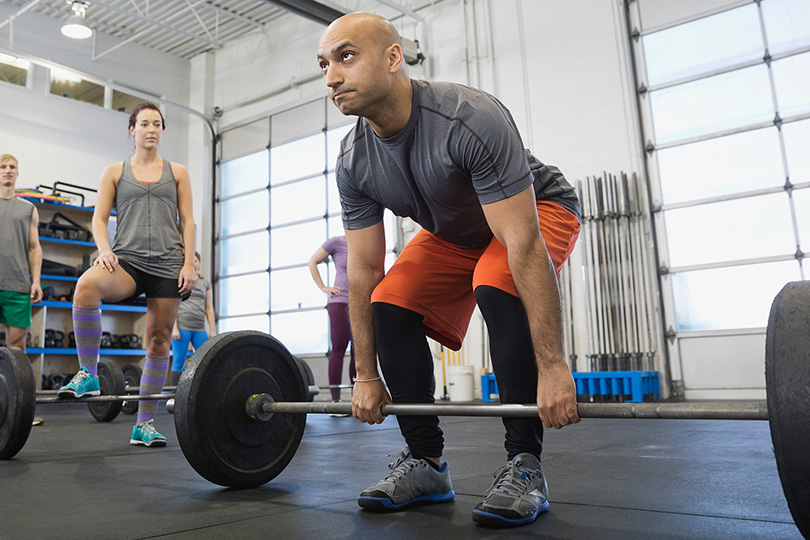 A man engaged in lifting a barbell at the gym, highlighting the role of exercise in maintaining testosterone levels.
