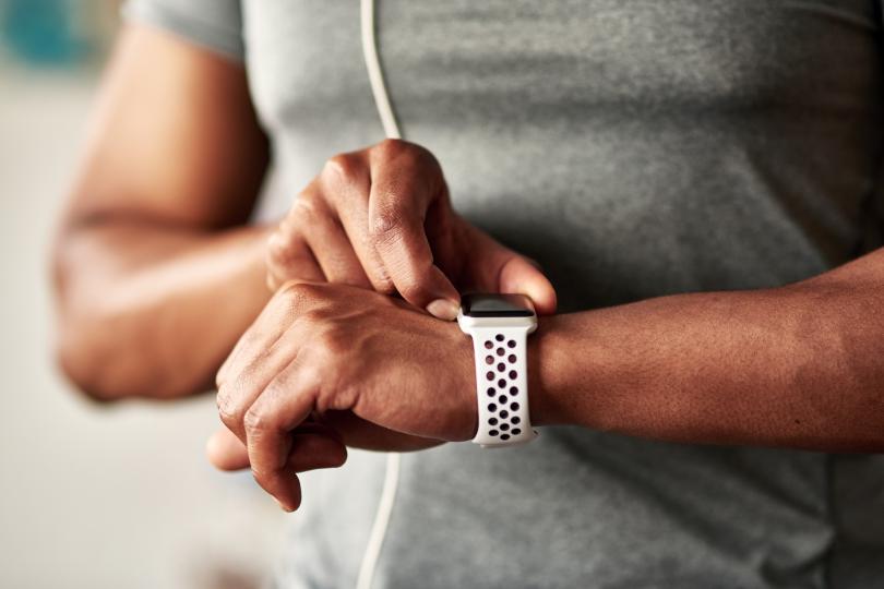 A man wearing headphones checks his watch, appearing focused and engaged in his surroundings.