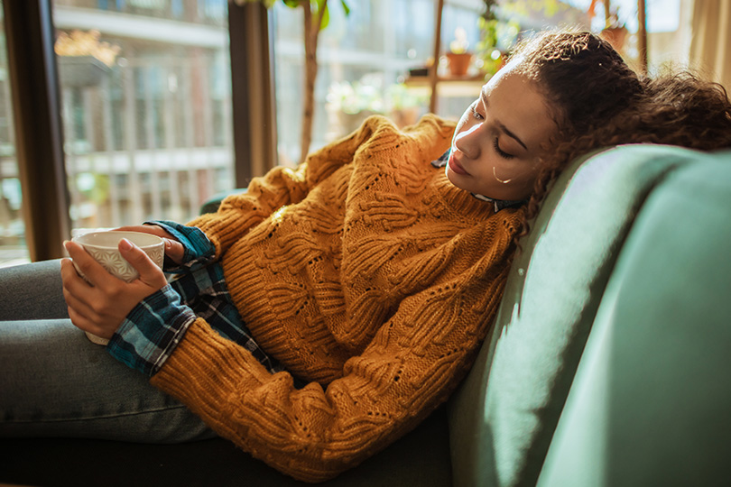 A woman lies on a couch, reflecting on inflammation and whether it always indicates a health concern.
