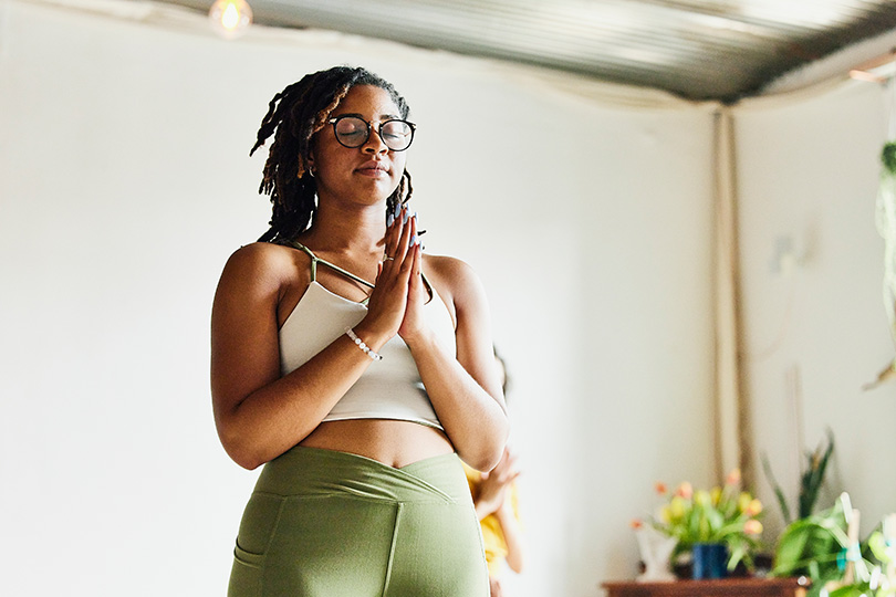 A woman in yoga poses in a well-lit room, showcasing her active lifestyle.
