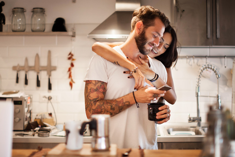A man and woman stand in a kitchen, engaged in a serious conversation about STIs and health awareness.