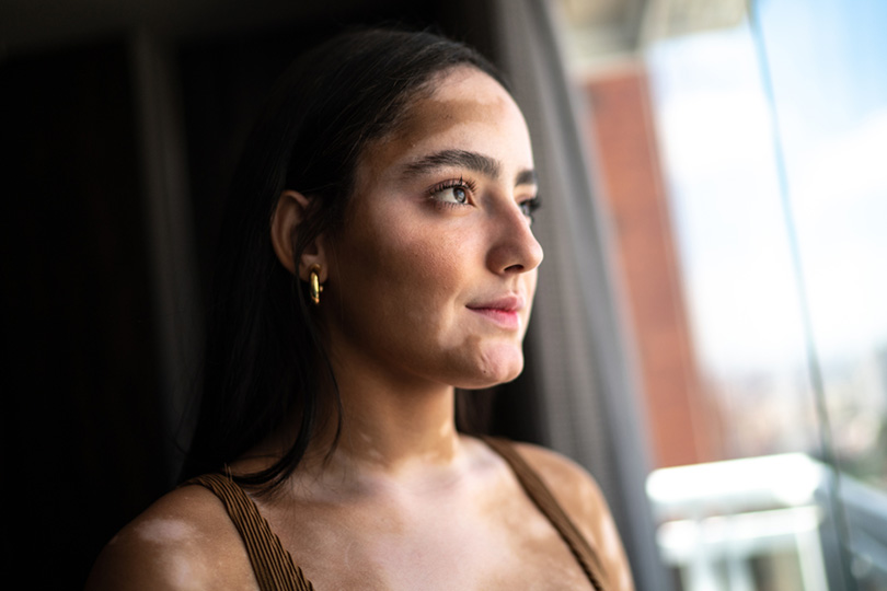 A woman with a tan complexion wearing elegant gold earrings, showcasing her style and confidence.