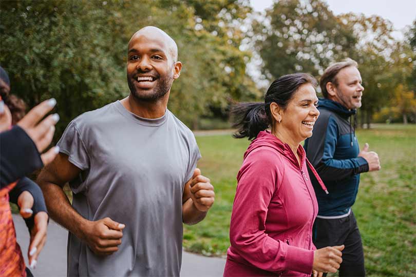 A group of men and women running outside, practicing heart-healthy habits that can help lower heart disease risk in people with high Lp(a) levels.