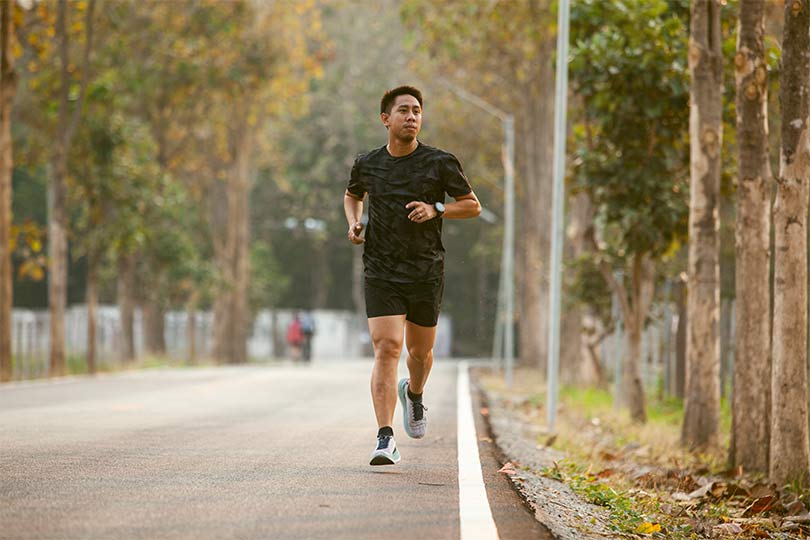 An Asian man running outside as part of his weight loss journey with GLP-1 medication.