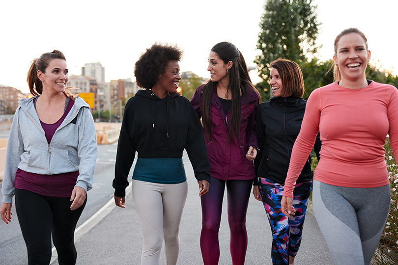 Five women walking side by side on a sidewalk, promoting awareness of heart disease and its impact on women's health.