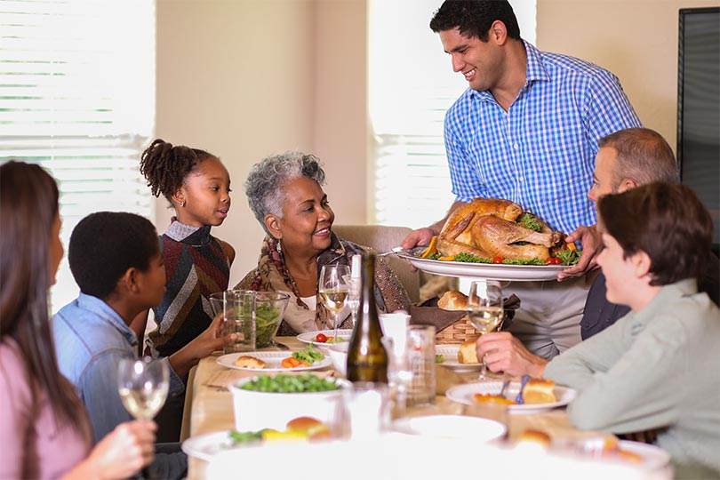A family gathered around the table for a holiday feast with inclusive food options for people with chronic conditions like food allergies, diabetes, celiac disease or liver disease.