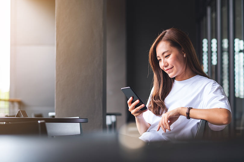 A woman scrolling on her phone and looking up Marker by Labcorp Genetic Health Panel, a test designed to help consumers identify genetic health risks and take a more proactive approach to managing long-term health.