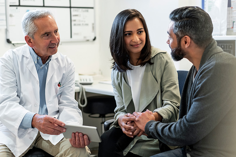A doctor engages with two individuals in a room, focusing on fertility issues related to low sperm count.