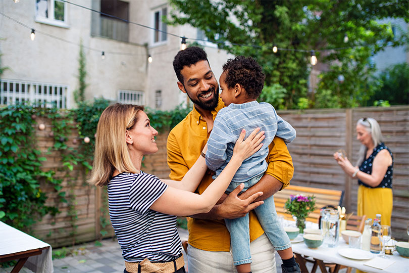 A white woman standing next to a Black man holding a young child