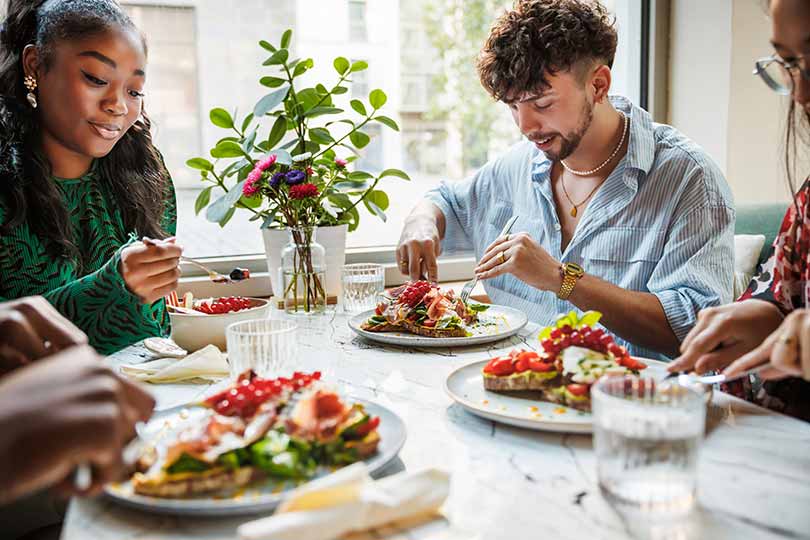A group of friends eating meals together, discussing the difference between metabolism and metabolic health.