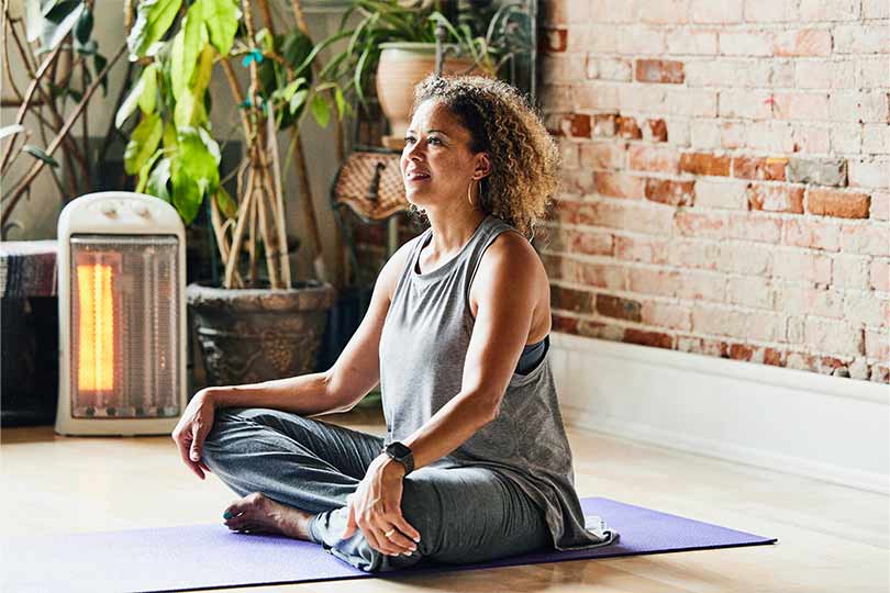 A woman is seated in a yoga pose on a mat, embodying tranquility and mindfulness, practicing science-based tips for healthy aging.