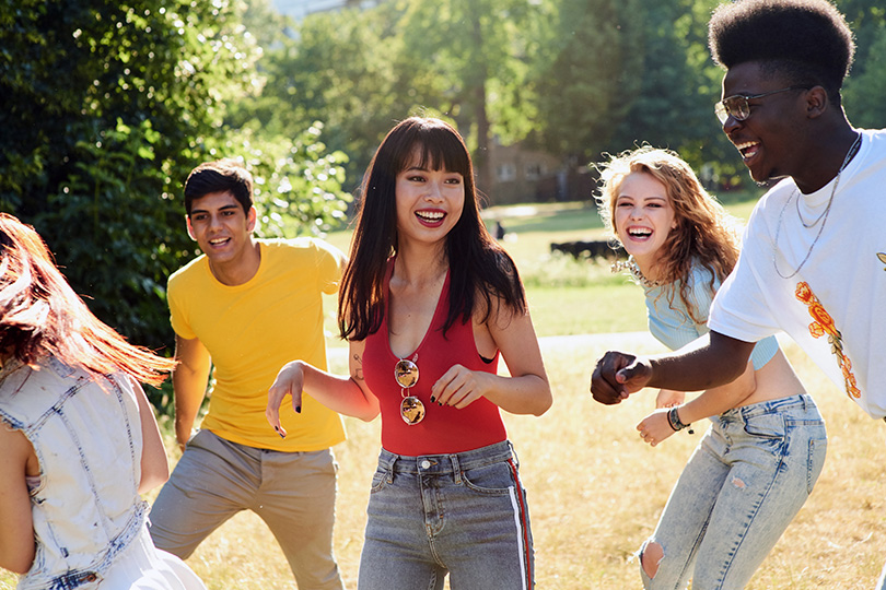 A lively group of young people enjoying a sunny day in the park, laughing and engaging in fun activities together.