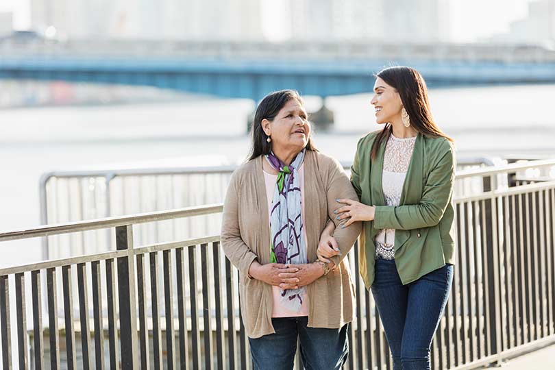 Two women walking along a waterfront and talking.