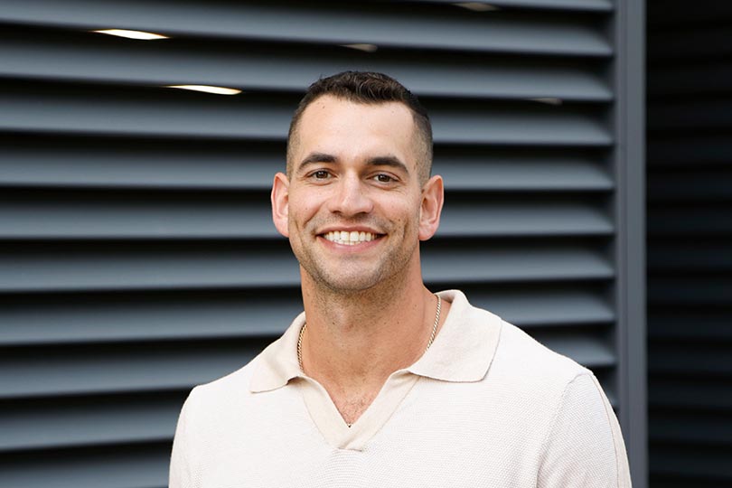 Jesse Solomon, Bravo reality star and testicular cancer survivor, stands smiling at the camera
