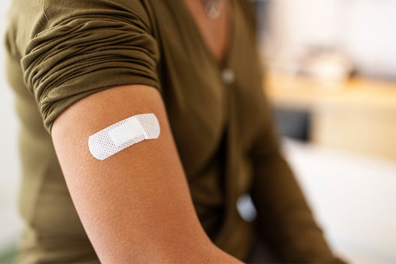 A close-up of a band-aid on a person’s arm after receiving a Tdap vaccine.