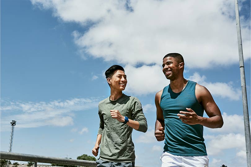 Two young men going for a run outside together, staying active to lower heart disease risk.