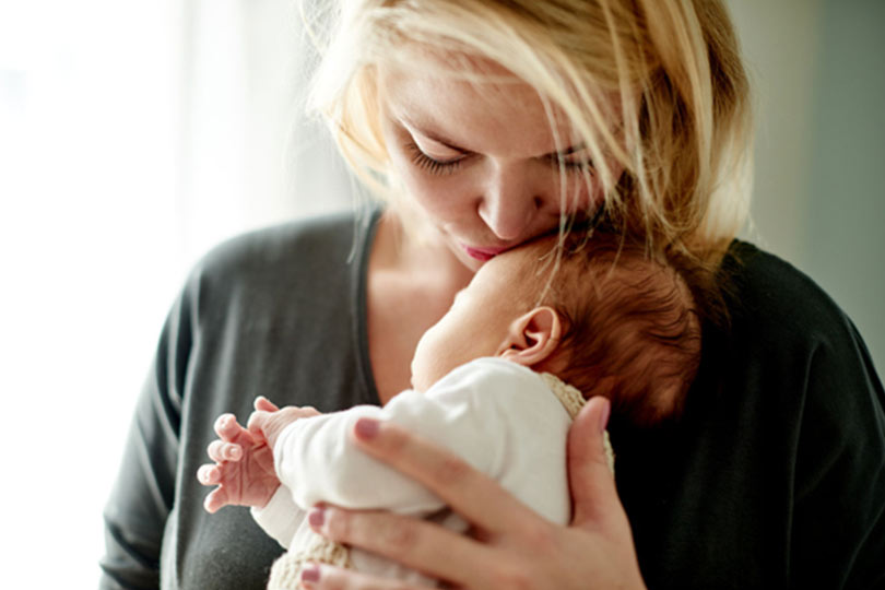 A postpartum woman holding her newborn baby.