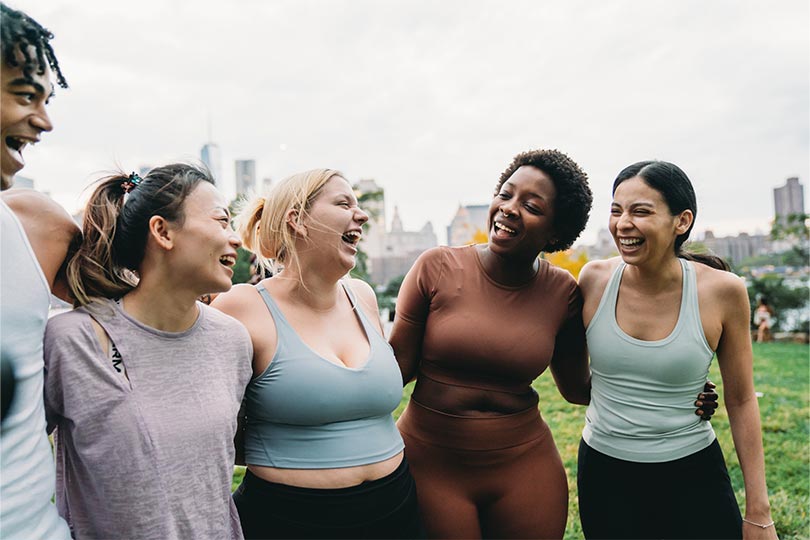 A group of women smiling and laughing together outside. Learn about what high or low testosterone in women can mean.