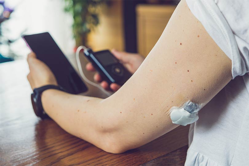 A person with diabetes who is using a continuous glucose monitor to check blood sugar levels.