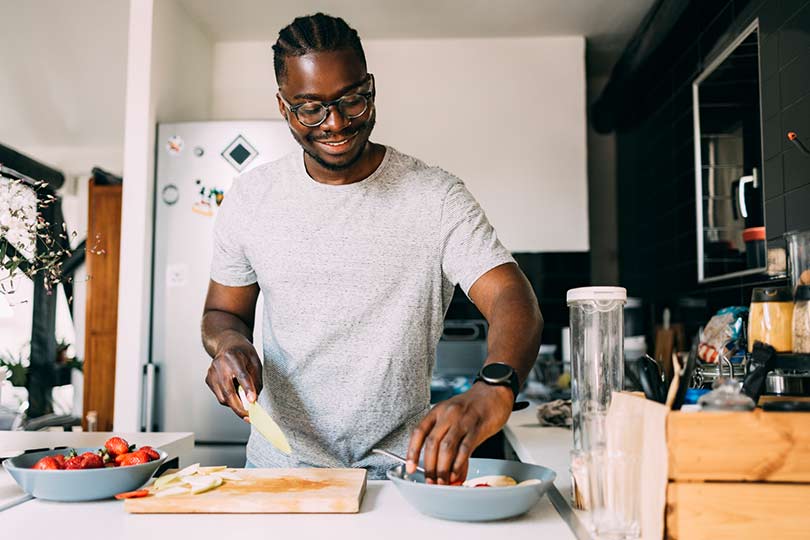 Person preparing fresh fruit in a kitchen, as part of a healthy diet supportive of digestive health and H. pylori management.