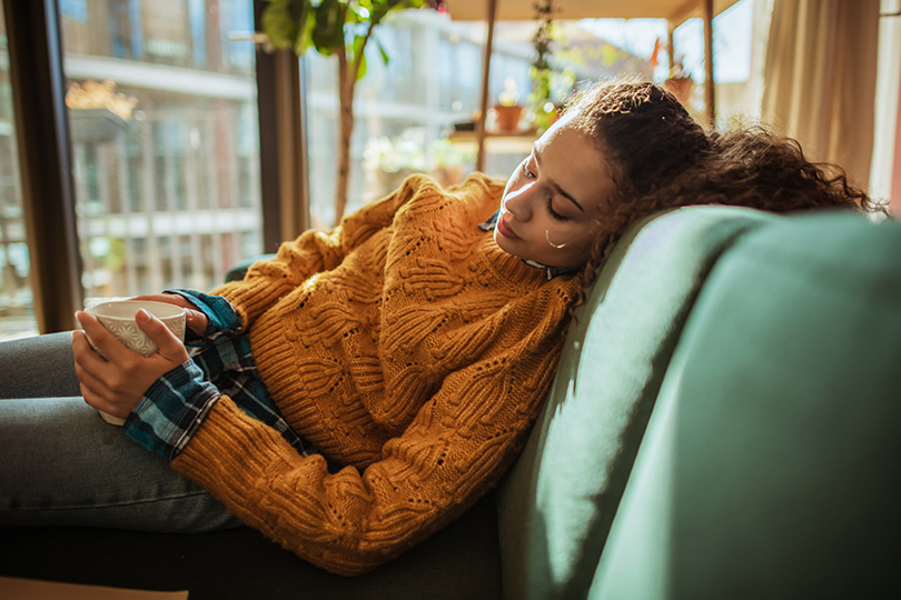 A woman lies on a couch, reflecting on inflammation and whether it always indicates a health concern.