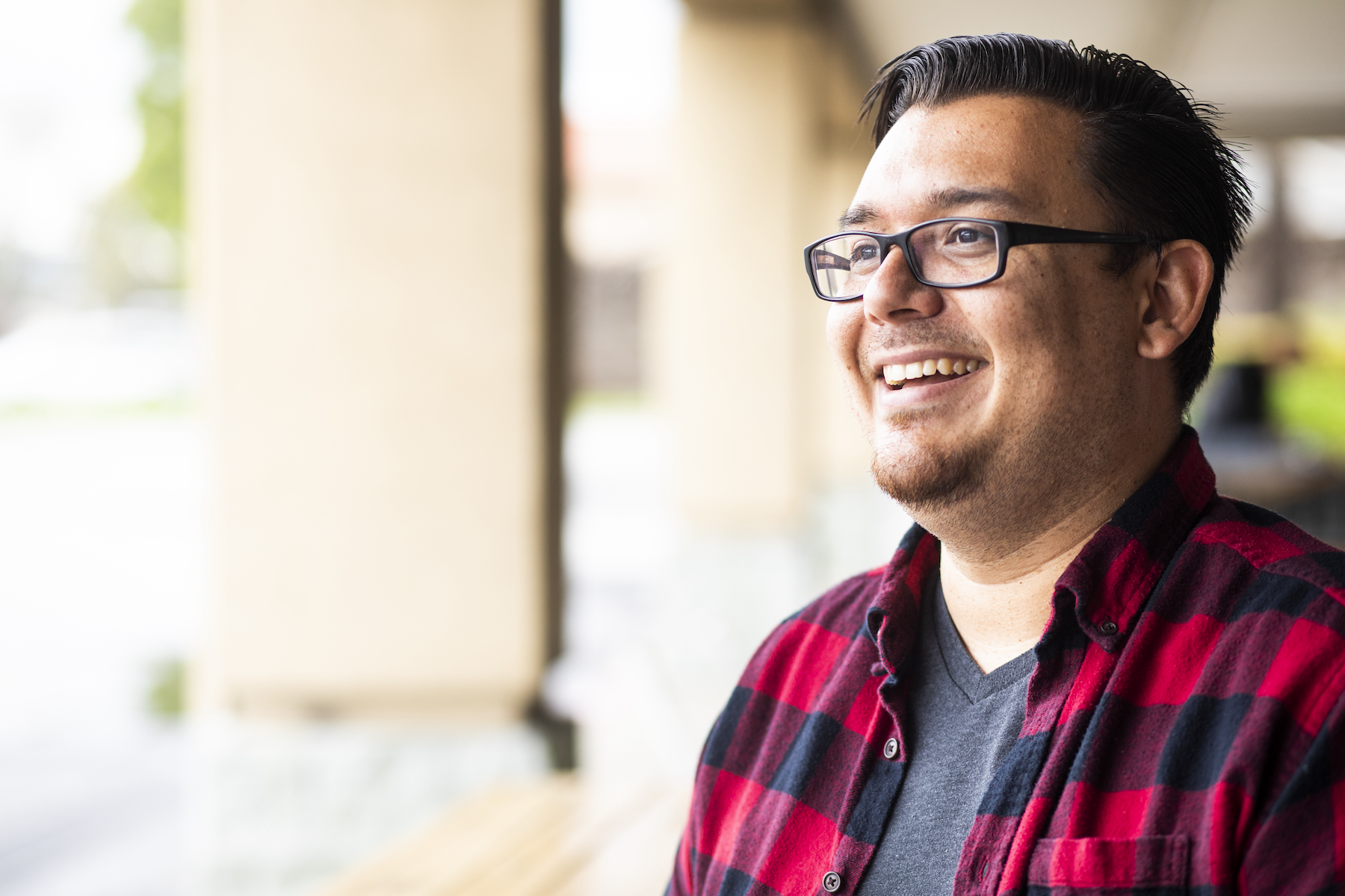 A man wearing glasses and a red and black plaid shirt, posing casually with a friendly expression.