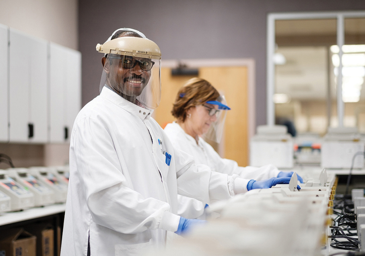 Two scientists in lab coats focused on electronic equipment, demonstrating teamwork in a laboratory.