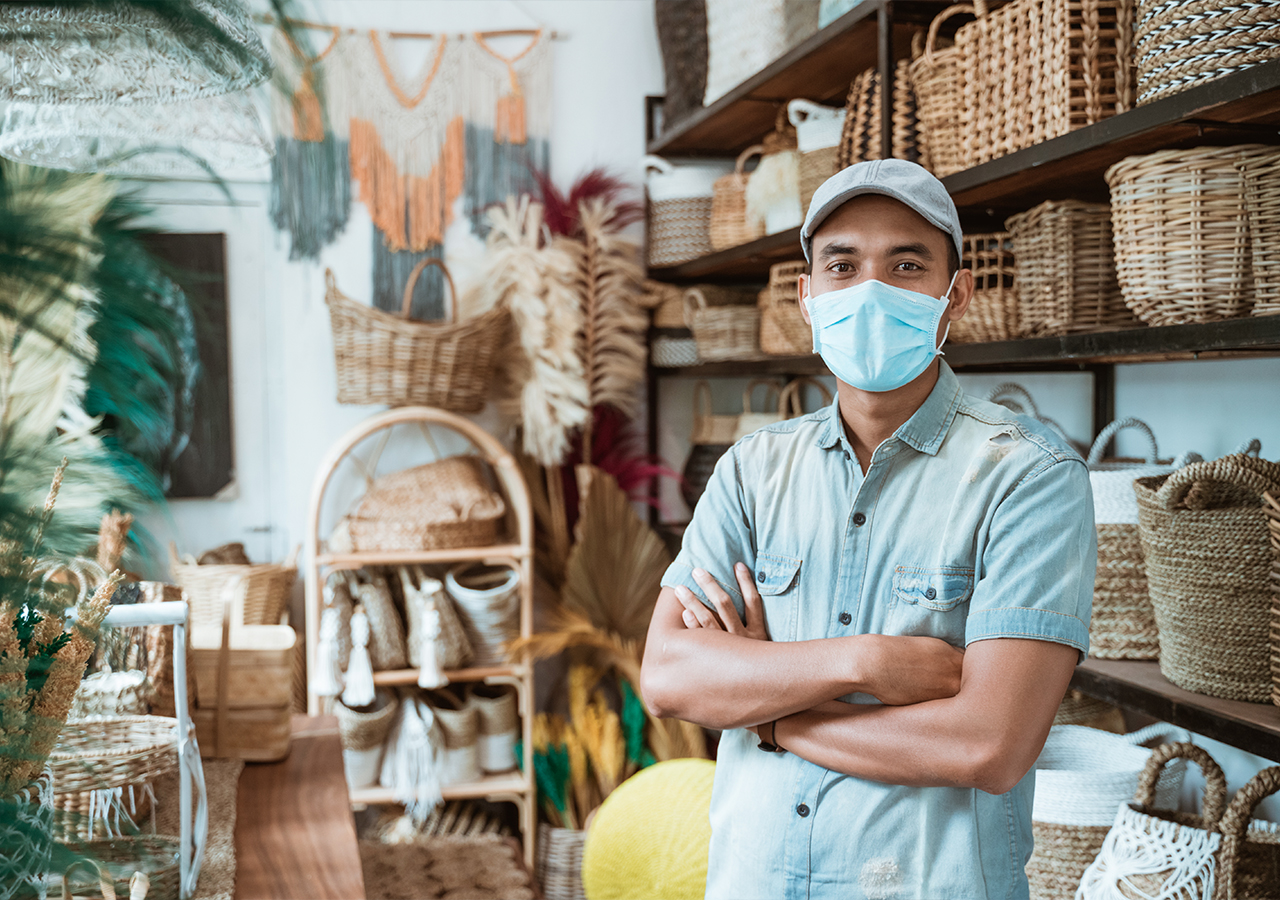 Masked man browsing in a shop with woven baskets and decorative items on display shelves.