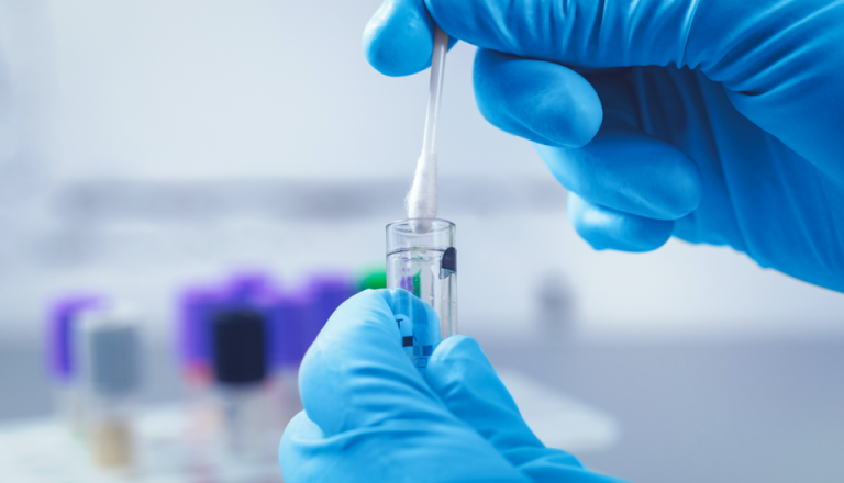 A person wearing blue gloves holds a test tube, preparing for a scientific experiment or analysis. 