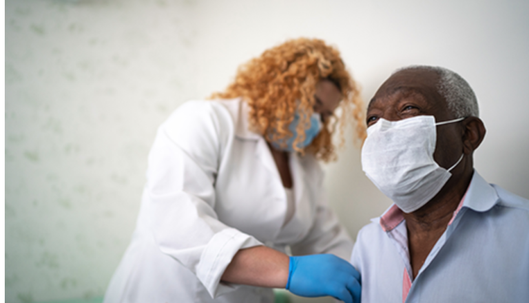 A doctor measures the temperature of an elderly man during a medical check-up in a clinical setting.
