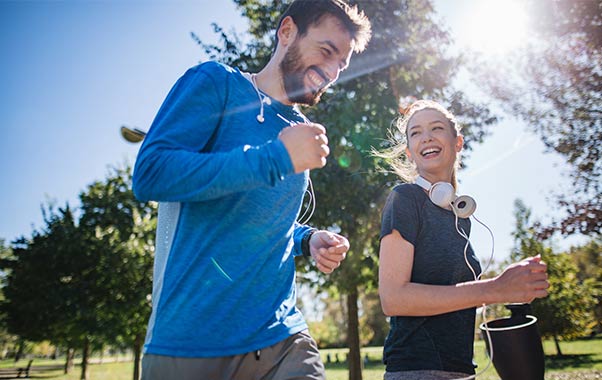 Two people jogging outdoors in sunlight