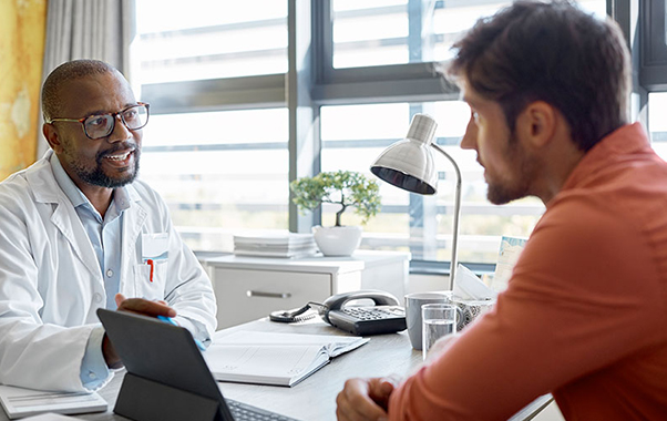 A man engages in conversation with a doctor in a clinical setting regarding the hormone health.