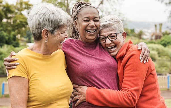 A group of women hugging after talking about healthy aging in women.