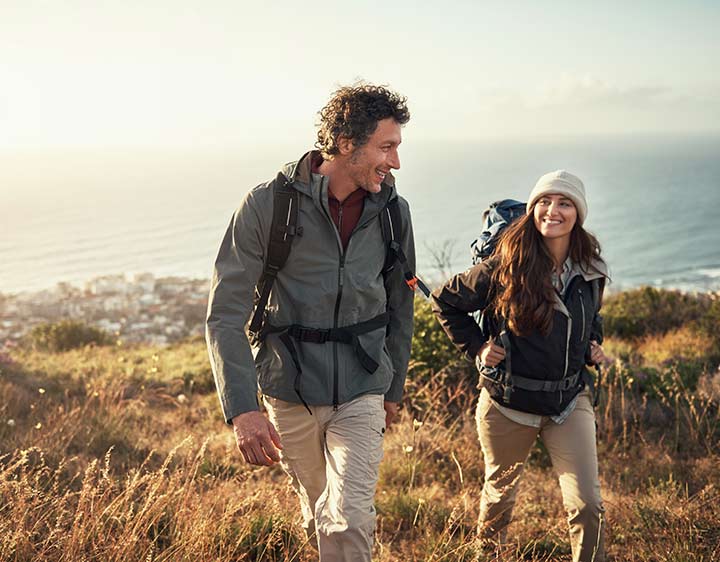 A man and woman are outside hiking and smiling