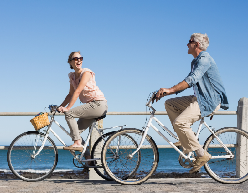 Couple takes bike ride by beach.