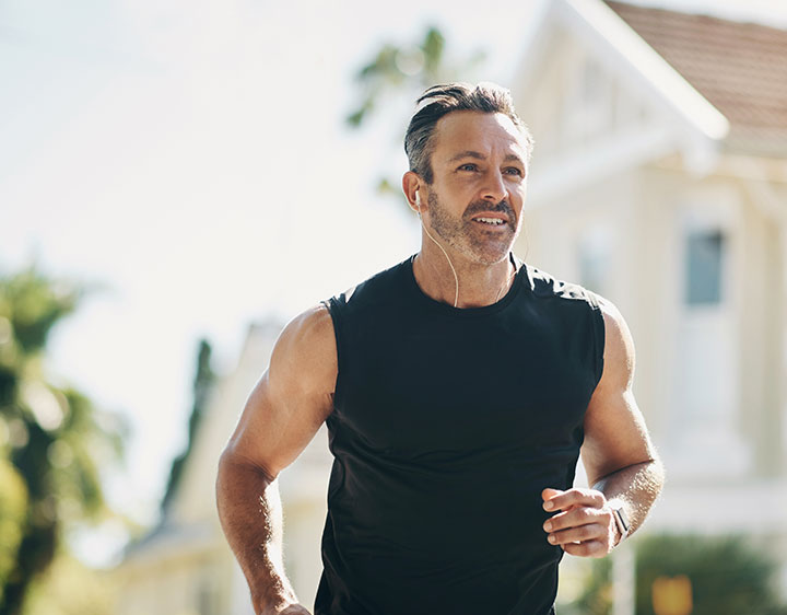 Middle aged man outdoors running monitoring health.