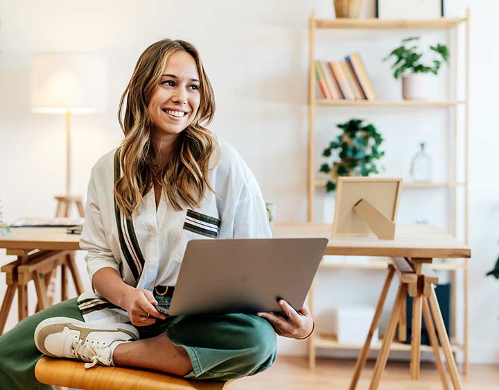 A happy woman sitting with a laptop in her home after seeing her test results