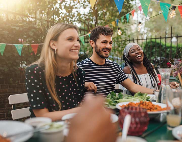 Friends sharing a meal outside together at a dining table