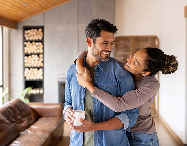A couple in a loving embrace in their living room, representing comfort while discussing herpes antibody test results.