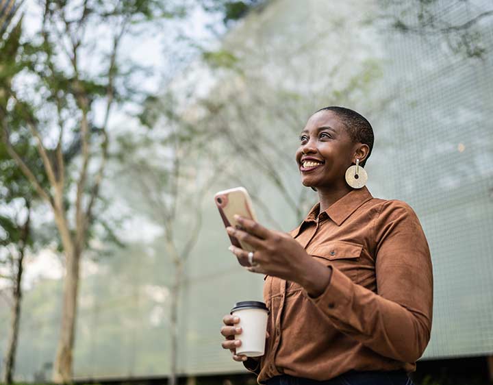 a woman smiles holding her phone outside after checking her test results