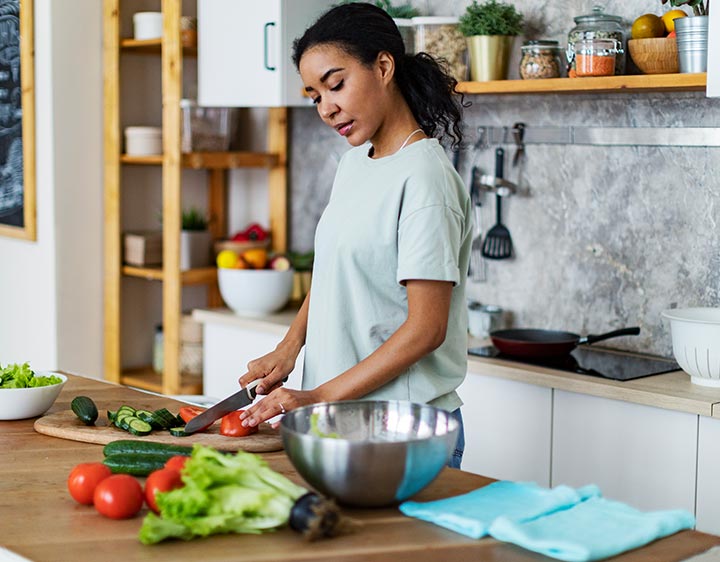 Woman chopping vegetables maintain selenium levels for health and wellness.