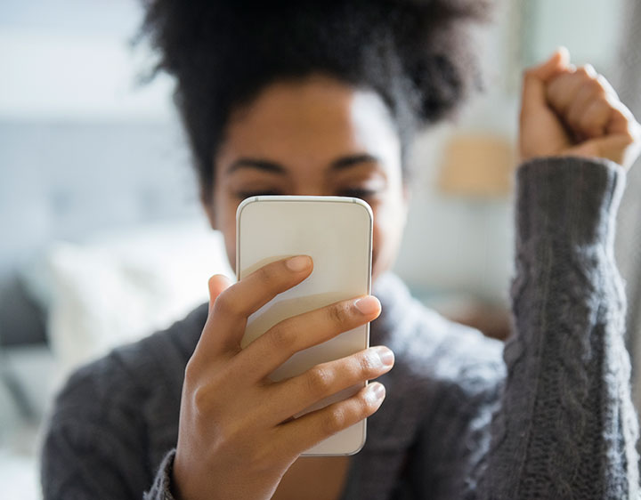 A woman sitting on a couch, holding a cell phone up to her face