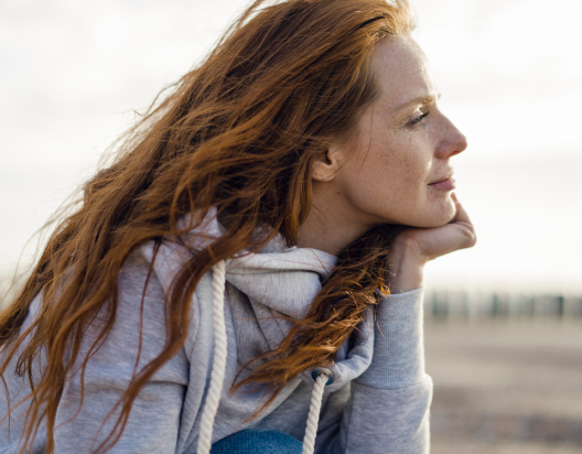 Woman on beach gazes out at water.