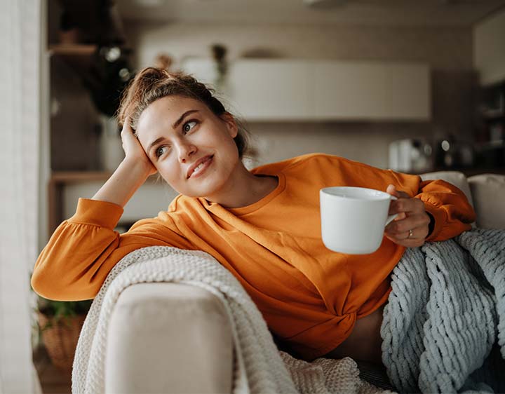 Woman sitting thoughtfully looking out of window, representing consideration of TPO Antibody testing.