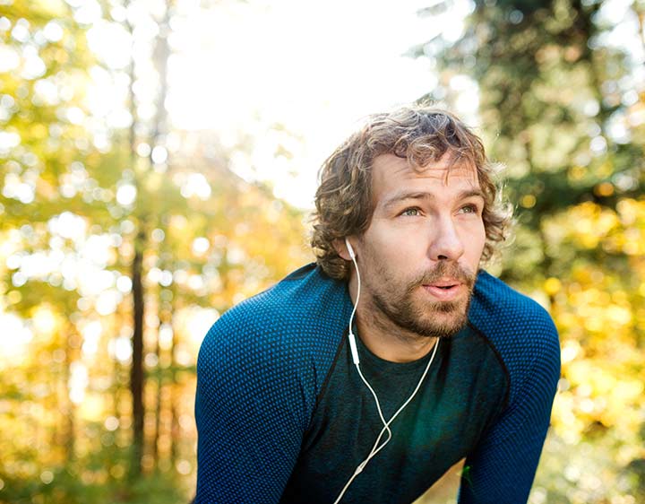 A man takes a short break from running while listening to headphones