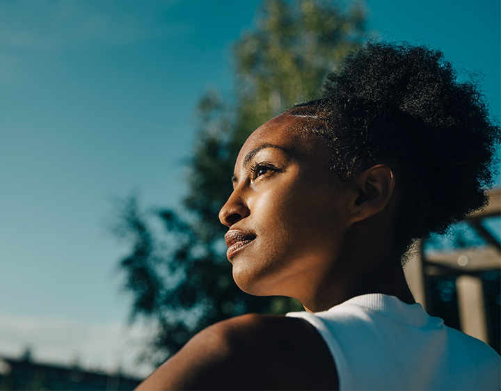 Confident sportswoman looking away in park on sunny day